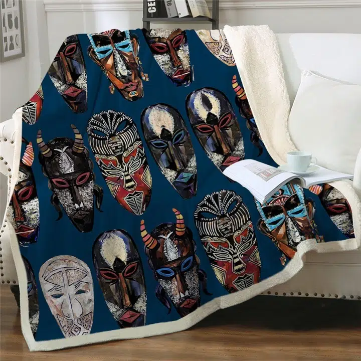 Plaid blau avec masques africains colorés étendu sur un canapé blanc avec livre et tasse posée dessus
