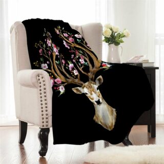 Couverture polaire motifs cerf bois fleuris noir sur un fauteuil dans un salon à la décoration claire.