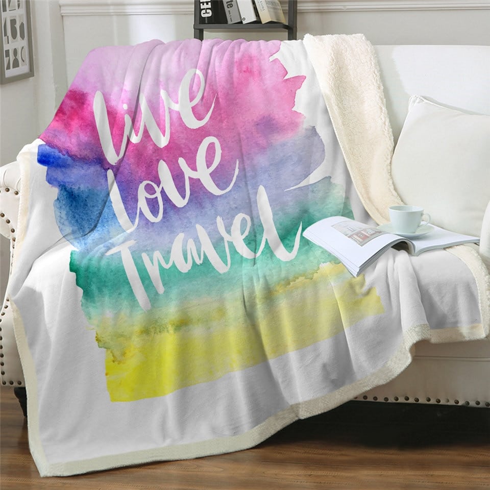 Couverture écriture mantra "vivre aimer voyager" sur un canapé