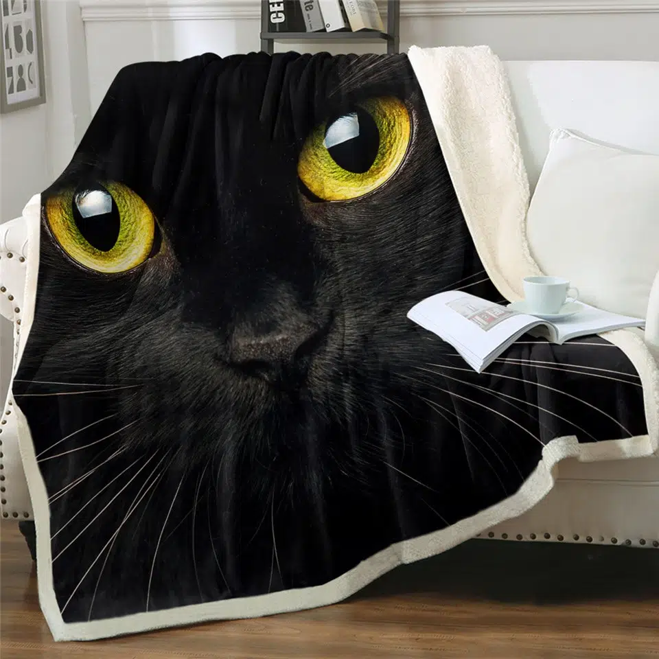 Couverture polaire tête de chat noir aux yeux jaunes sur un canapé