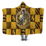 Plaid jaune et marron de la saga Harry potter avec l'écusson central des Hufflepuff avec un blaireau en icone. Autour du symbole, il y a de nombreux écussons de cette maison.