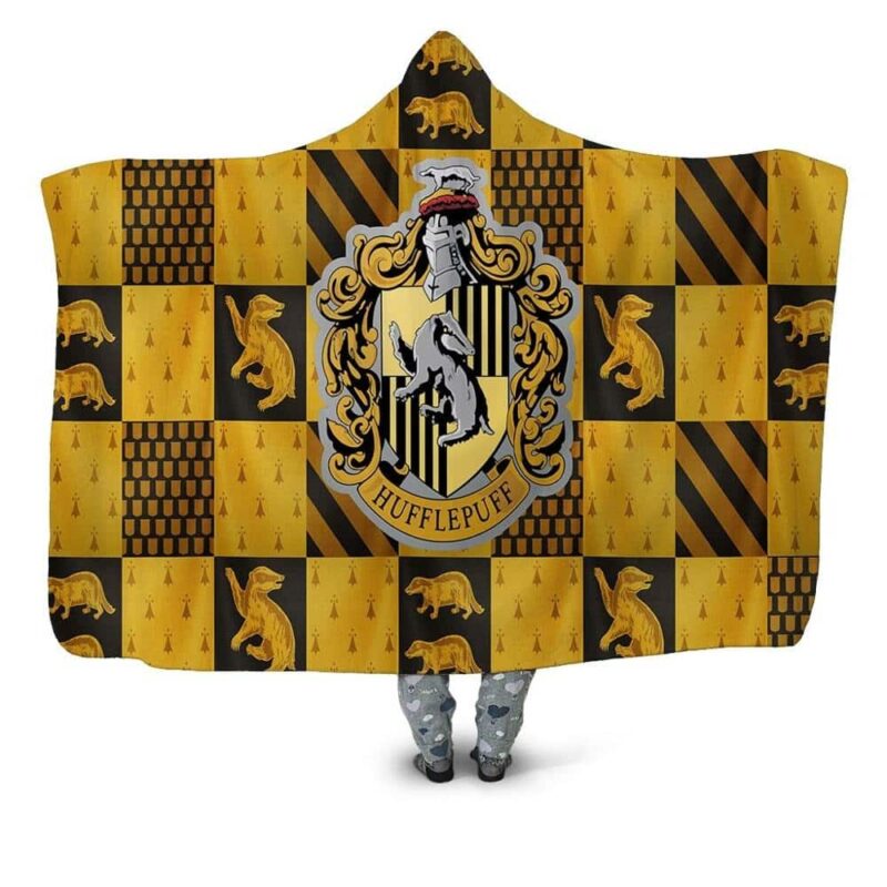 Plaid jaune et marron de la saga Harry potter avec l'écusson central des Hufflepuff avec un blaireau en icone. Autour du symbole, il y a de nombreux écussons de cette maison.