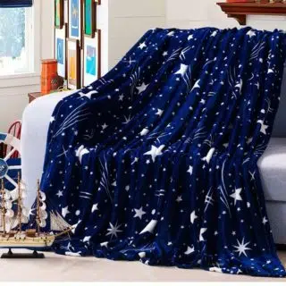 Plaid bleu avec étoiles blanches sur canapé gris dans une chambre avec bateau au sol