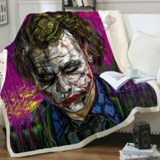 Plaid multicolore imprimé tête du Joker sur un canapé blanc et débordant sur le sol en parquet marron.
