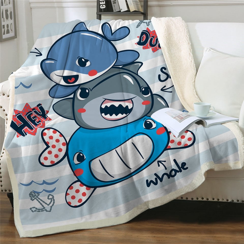 Plaid enfant avec 3 bébés requins dessinés sur un canapé blanc