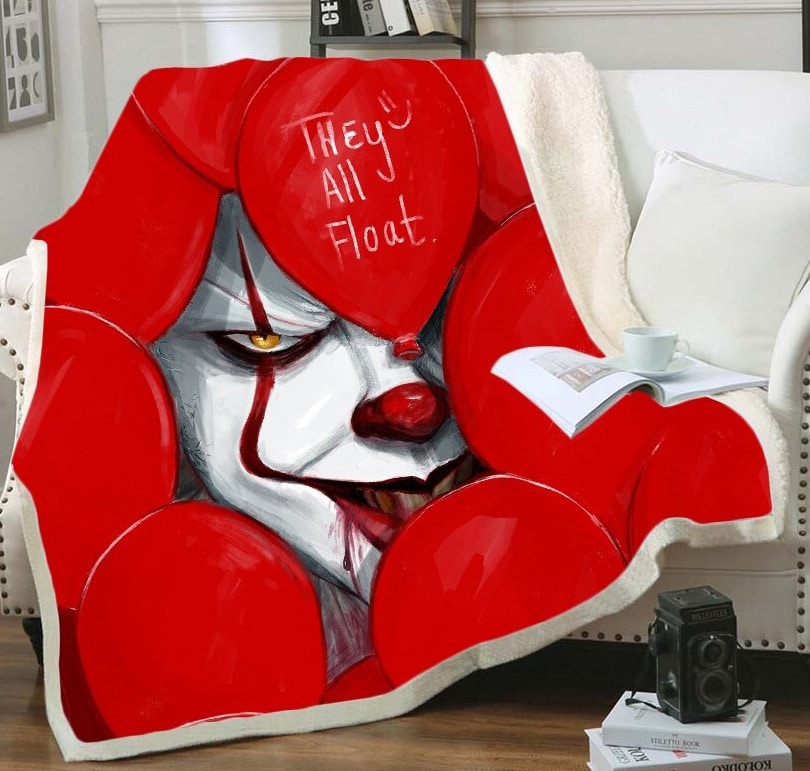 Plaid rouge avec motif Thriller avec visage du clown CA entouré de ballons rouges 3D sur un canapé blanc . Il y a un livre ouvert sur le dessus avec une tasse blanche posée par- dessus.