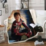 Plaid en polaire réaliste à l'effigie de Peter Parker dans des couleurs sombres. Le plaid est étendu sur un canapé blanc dans un décor de salon.