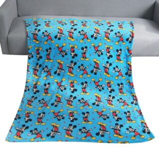 Plaid polaire bleu avec plein de mickey en mouvement étendu sur l'assise d'un canapé en simili cuir gris