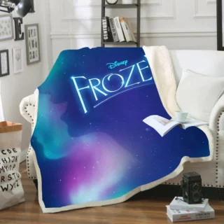 Plaid polaire bleu de la reine des neiges avec nuances de roses avec écriture "Frozen -Disney". Il est étendu sur un canapé blanc dans un décor de salon.