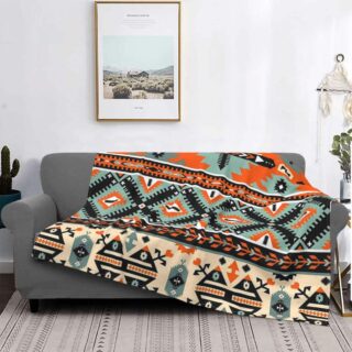 Plaid avec motifs amérindiens multicolore étendu sur un canapé gris avec un cadre en arrière-plan sur mur blanc