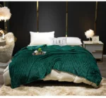 Couverture vert sapin en flanelle côtelée servant de couvre-lit sur un grand lit 2 places à barreaux dorés dans un décor de chambre au mur noir.