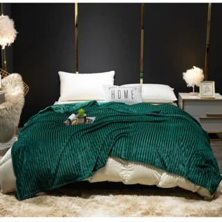 Couverture vert sapin en flanelle côtelée servant de couvre-lit sur un grand lit 2 places à barreaux dorés dans un décor de chambre au mur noir.