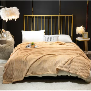 Couverture beige en flanelle côtelée beige servant de couvre-lit sur un grand lit 2 places à barreaux dorés dans un décor de chambre au mur noir.