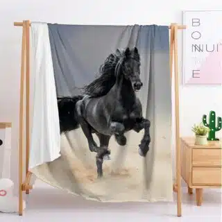 Dans une chambre à la décoration scandinave et minimaliste, on voit une couverture en sherpa ornée d'un cheval noir au galop.