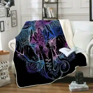Dans un salon avec des murs blancs et des moulures, on voit un canapé blanc recouvert d'un plaid noir avec une grosse tête d'éléphant de toutes les couleurs.