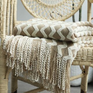 Plaid décoratif en fil beige naturel avec franges et motifs croisillons sur chaise en osier tressée