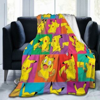 Plaid polaire avec carrés multicolores avec plusieurs Pikachu dans des états d'émotions différentes. Il est étendu sur un fauteuil gris foncé et déborde sur un sol en parquet gris.