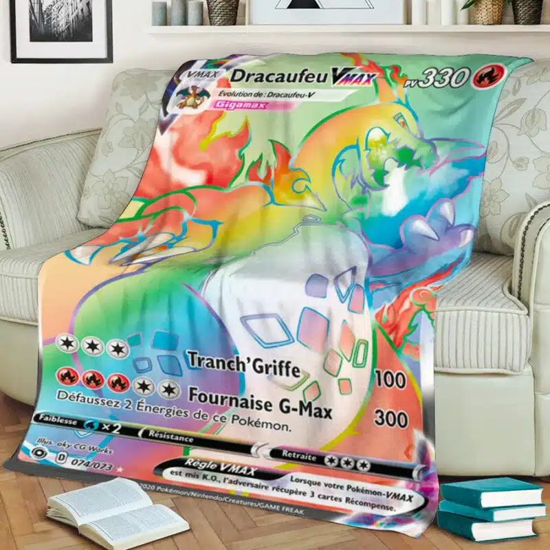 Plaid polaire multicolore carte Pokémon Giga-Dracaufeu VMAX étendu sur un canapé beige à fleurs dans un salon. Il y a une pile de 3 livres et un livre ouvert sur le sol .