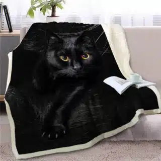 Plaid avec motif de chat noir aux yeux jaunes posé sur un canapé gris