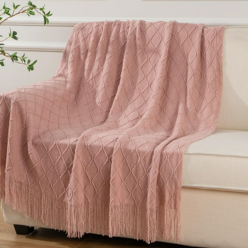 Plaid rose à carreaux posé sur un canapé en cuir blanc sur un parquet et devant un mur blanc