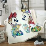 Plaid Mickey et Minnie en cartoon multicolore posé sur un canapé blanc dans un salon avec du parquet