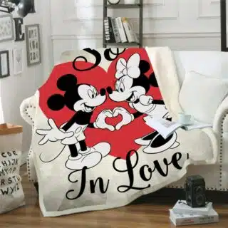 Plaid Mickey et Minnie en cartoon noir et blanc avec un grand coeur rouge posé sur un canapé blanc dans un salon avec du parquet