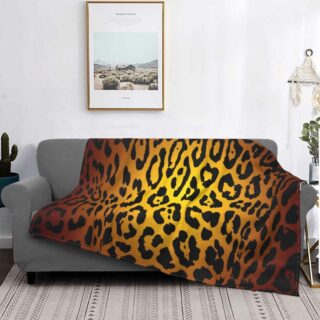canapé gris dans un salon avec un plaid au motif léopard aux couleurs profondes, avec un tableau au dessus
