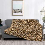 canapé gris dans un salon avec un plaid au motif léopard beige, avec un tableau au dessus