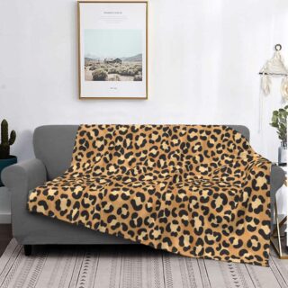 canapé gris dans un salon avec un plaid au motif léopard beige, avec un tableau au dessus