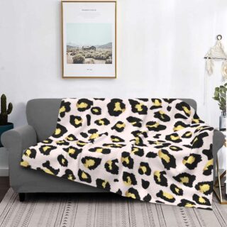 canapé gris dans un salon avec un plaid au motif léopard beige et jaune, avec un tableau au dessus