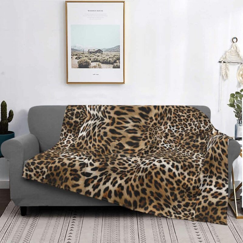 canapé gris dans un salon avec un plaid au motif léopard, avec un tableau au dessus