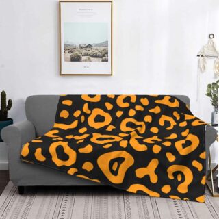 canapé gris dans un salon avec un plaid au motif léopard orange, avec un tableau au dessus
