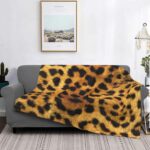 canapé gris dans un salon avec un plaid au motif léopard réaliste, avec un tableau au dessus