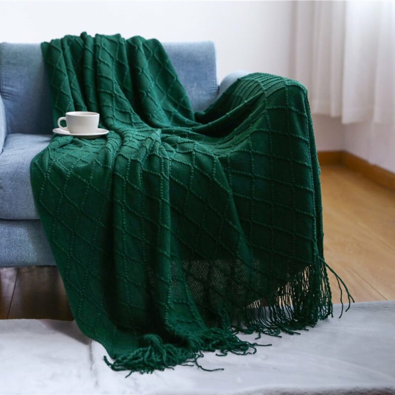 sur un canapé gris clair un plaid vert émeraude installé avec une tasse à café posé dessus