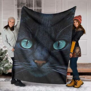 deux jeunes femmes tiennent ouvert pour que l'on voit le motif, un plaid avec une tête de chat noir vue de près et dont les yeux sont bleus et perçants