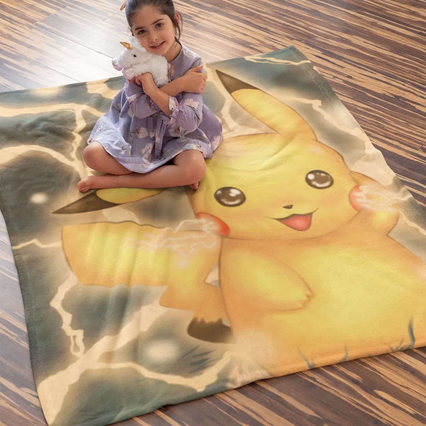 Un plaid pikachu et posé sur le sol en parquet, une petite fille est assise dessus.