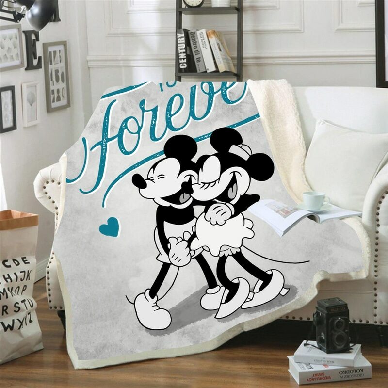 sur un canapé blanc dans un salon , un plaid est installé et représente Mickey et minnie enlacés avec une inscription écrit Forever