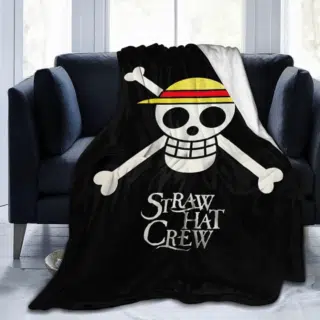 Plaid One piece représentant le symbole pirate du manga un squelette avec un chapeau de paille, posé sur un canapé noir devant une fenêtre