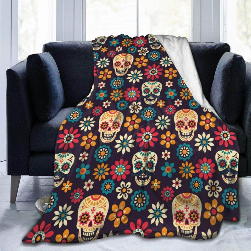 Plaid tête de mort mexicaines et fleurs sur fond noir présenté sur un canapé noir