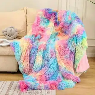 Couverture couleurs peps en fausse fourrure déposée sur un canapé dans un salon.