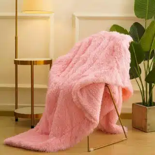 Plaid en fausse fourrure rose vif posé sur un fauteuil dans un salon.