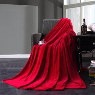 Couverture polaire peluche en version rouge, sur un fauteuil, dans un salon.