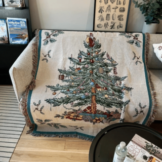 Couverture arbre de Noël dépliée sur un canapé dans un salon.