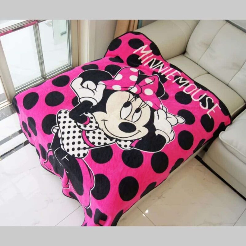 Plaid noir et rose Minnie, qui est rose fuschia avec de gros pois noir, sur un canapé dans un salon.