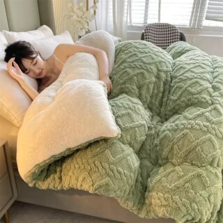 Couverture de lit épaisse double face pondérée en version verte qui couvre une jeune femme dans son lit.