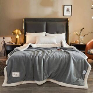 Couverture lourde et chaude en polaire, en version grise, disposée sur un lit dans une chambre à coucher.