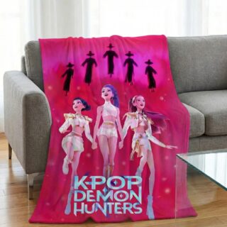 Un grand Plaid Kpop Demon Hunters Huntrix et Saja Boys rose vif posé sur un canapé gris, illustrant trois jeunes filles stylisées en tenues blanches devant des silhouettes mystérieuses, dans un salon lumineux avec un sol en bois.
