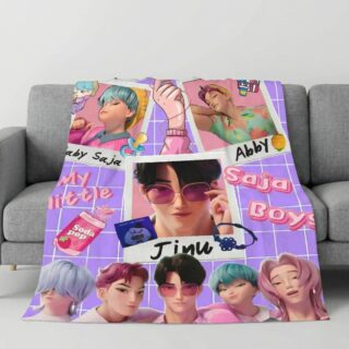 Un Plaid Kpop Demon Hunters Saja Boys posé sur un canapé gris, affichant des illustrations colorées de personnages de style méchas et manga sur un fond violet quadrillé.